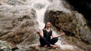 Kadın taş şelale ile yoga yaparken
