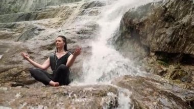 Kadın taş şelale ile yoga yaparken