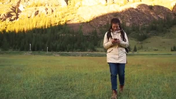 Wandelaar vrouw lopen op veld chat met behulp van smartphone — Stockvideo