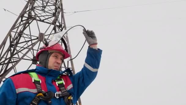 Elettricista uomo in piedi sulla linea elettrica e casco aperto — Video Stock