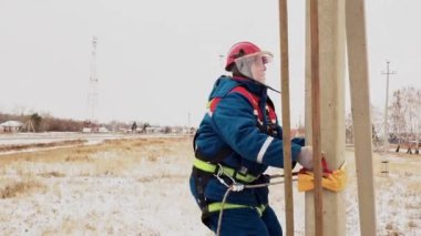 Kasklı elektrikçi direğin kemerini kullanarak güç hattına yükseltildi