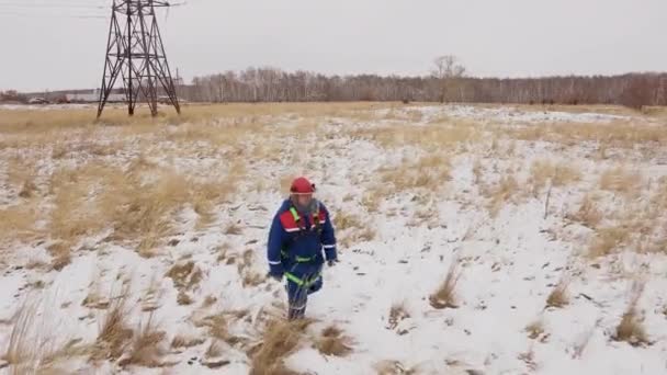 Elektriker mannen som går på snön fältet vid elektriska stationen — Stockvideo
