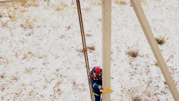 Elettricista in tuta e casco arrampicata al palo della tensione — Video Stock