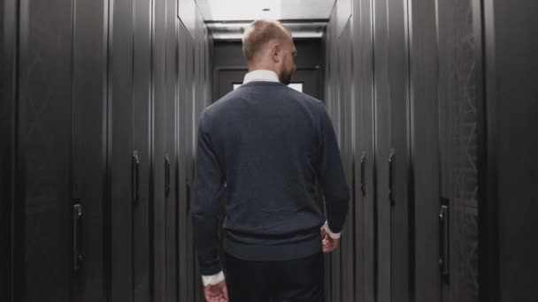 Hombre técnico caminando más allá de la sala de servidores de la cámara lenta del centro de datos — Vídeo de stock