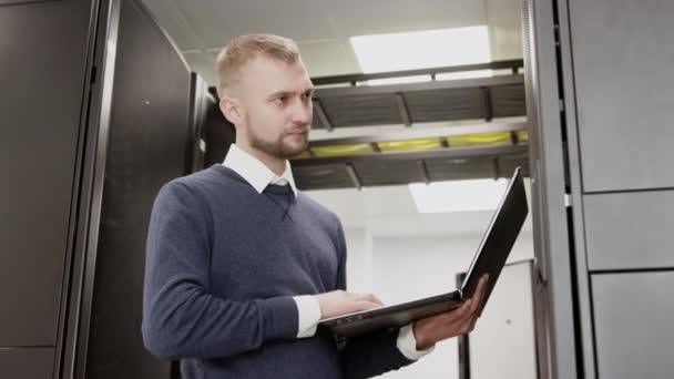 Administrador do sistema segurando laptop em pé antes do rack do servidor — Vídeo de Stock