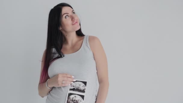 Schwangere in grauem Hemd posiert. Porträt der Mutter mit Scan des Babys. — Stockvideo