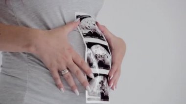 Gri tişörtlü esmer hamile kadın pozları. Ultrason Taraması Olan Anne.