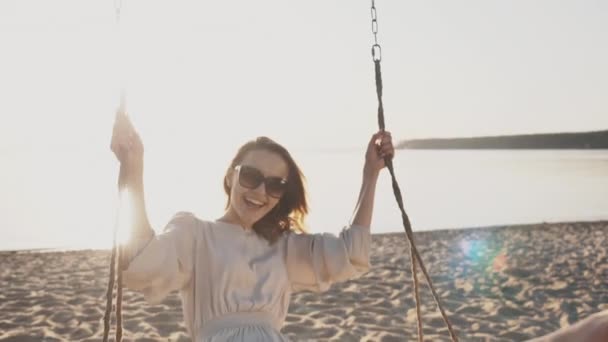 Lächelndes glückliches Mädchen wiegt sich auf Schaukel, unbeschwerte Freiheit, entspannte Freude auf lustigem Seebad — Stockvideo