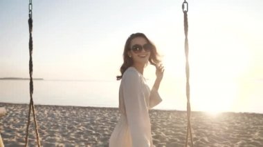 Genç, mutlu, gülümseyen kız deniz sahilinde yürüyor, kaygısız cennetin tadını çıkarıyor.