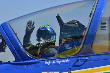 PIRASSUNUNGA, BRAZIL - May 13, 2017 - 65th celebration of the Smoke Squadron. View of the cockpit before the air shows start, pilot waving. clipart