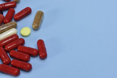 Renkli tablet ve kapsül mavi arka plan üzerinde üstten görünüm.