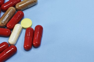 Renkli tablet ve kapsül mavi arka plan üzerinde üstten görünüm.