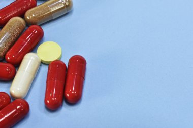 Renkli tablet ve kapsül mavi arka plan üzerinde üstten görünüm.