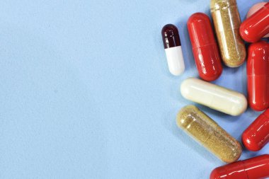 Renkli tablet ve kapsül mavi arka plan üzerinde üstten görünüm.