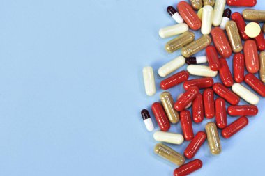 Renkli tablet ve kapsül mavi arka plan üzerinde üstten görünüm.