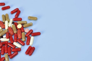 Renkli tablet ve kapsül mavi arka plan üzerinde üstten görünüm.