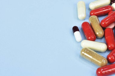 Renkli tablet ve kapsül mavi arka plan üzerinde üstten görünüm.