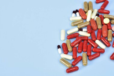 Renkli tablet ve kapsül mavi arka plan üzerinde üstten görünüm.