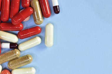 Renkli tablet ve kapsül mavi arka plan üzerinde üstten görünüm.