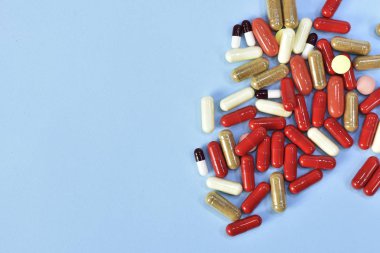 Renkli tablet ve kapsül mavi arka plan üzerinde üstten görünüm.