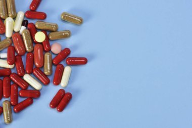 Renkli tablet ve kapsül mavi arka plan üzerinde üstten görünüm.
