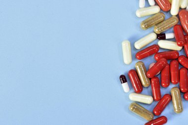 Renkli tablet ve kapsül mavi arka plan üzerinde üstten görünüm.