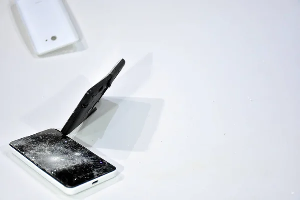 Cell phone with the screen broken by a hammer. Smart phone with the Screen knitted. Cell phone broken by a hammer. White background with mobile phone with splintered screen.