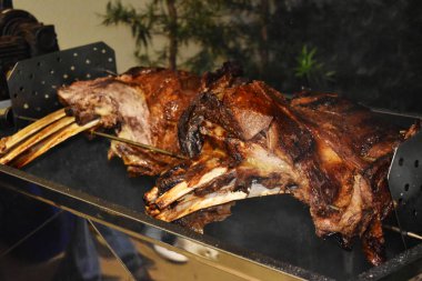 Büyük bir parça sığır kaburgası silindirin üzerinde kavrulmuş. Birçok kişi için et barbekü. Kavrulmuş biftek. Kemikte biftek.