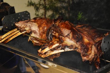 Büyük bir parça sığır kaburgası silindirin üzerinde kavrulmuş. Birçok kişi için et barbekü. Kavrulmuş biftek. Kemikte biftek.