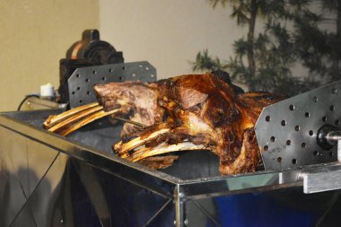 Büyük bir parça sığır kaburgası silindirin üzerinde kavrulmuş. Birçok kişi için et barbekü. Kavrulmuş biftek. Kemikte biftek.