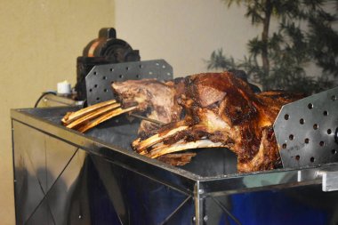 Büyük bir parça sığır kaburgası silindirin üzerinde kavrulmuş. Birçok kişi için et barbekü. Kavrulmuş biftek. Kemikte biftek.