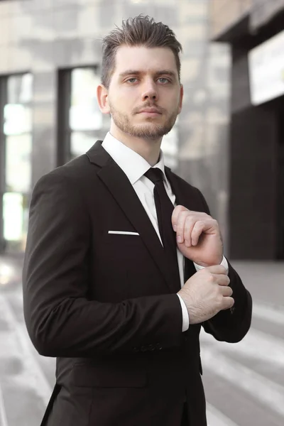 Hombre de negocios ajustando su corbata en la entrada del edificio de oficinas — Foto de Stock