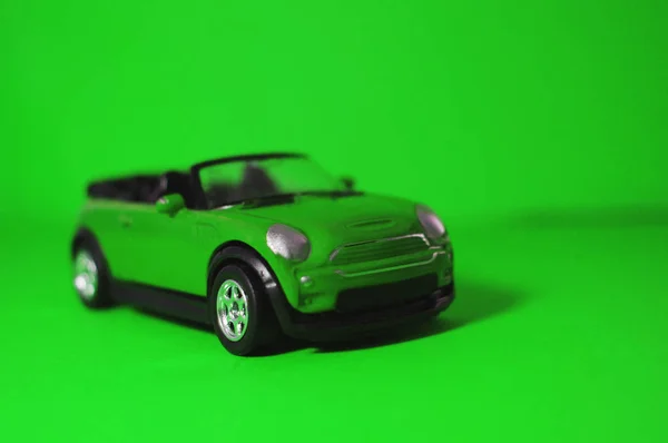 Pequeño juguete SUV verde, coche de juguete para niños con una parte superior abierta sobre un fondo verde — Foto de Stock