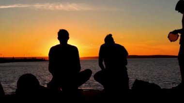 Siluetleri göl günbatımı kumsalda davul ile müzik grubu