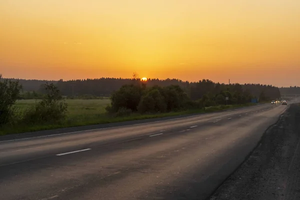 Samochody Kraju Asfaltową Drogą Lesie Zachodzie Słońca — Zdjęcie stockowe
