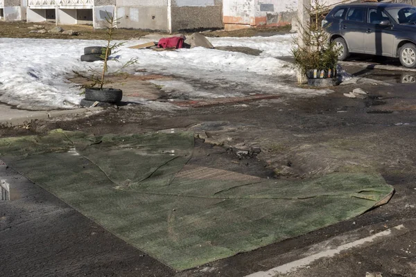 City dwellers covered pits of terrible road with old carpets in spring