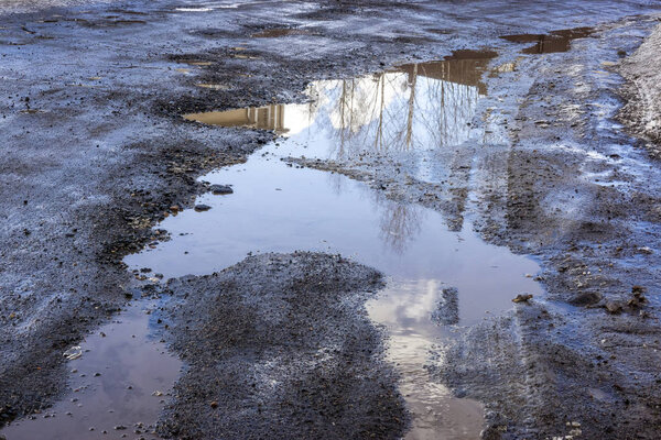 Плохая дорога с ямами и лужами в весенний день
