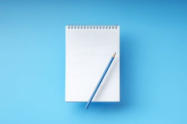 Mavi arka plan üzerinde boş beyaz kontrol defter sayfası ve kalem