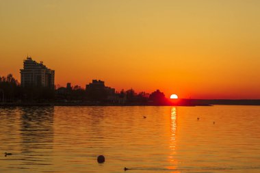 Yaz gün batımında göl üzerinde Cityscape siluet görünümü