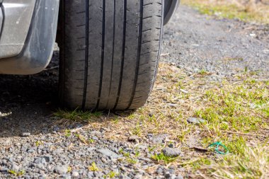 Yaz gezisi sırasında çakıllı yolda araba tekerleğinin pejmürde lastiği.
