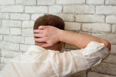 Stresli ya da yorgun adam kafasını duvara dayadı.