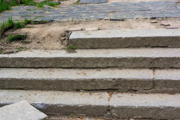 Broken concrete steps on sidewalk in summer street