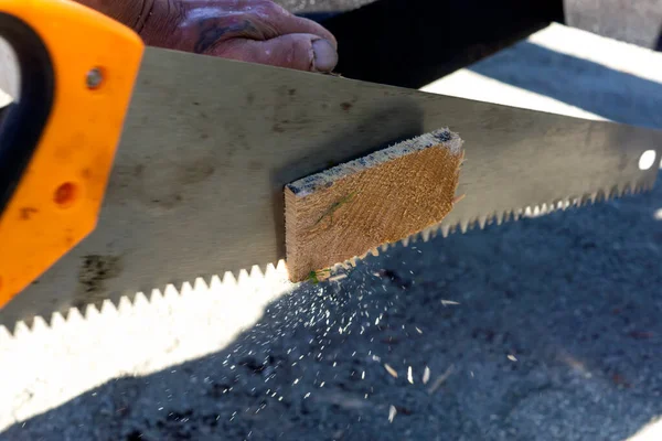 建筑工人用粗糙的手锯锯木木板 — 图库照片