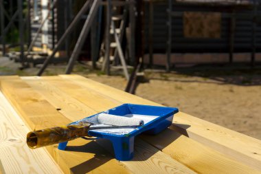 Boya rulosu ve boyanmamış çam tahtalarına beyaz boya ile boya banyosu