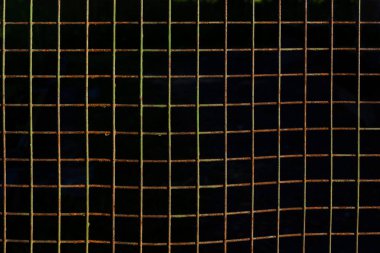 Paslı metal çitlerden yapılmış kare hücreler, soyulmuş boya, koyu arkaplan desenli.