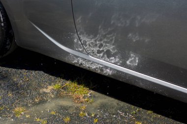 Güneş bir su birikintisinde parıldıyor ve makinenin yüzeyinde, arka planda