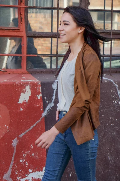 Bir kaldırım boyunca kentsel bir sokakta yürüyen kadın