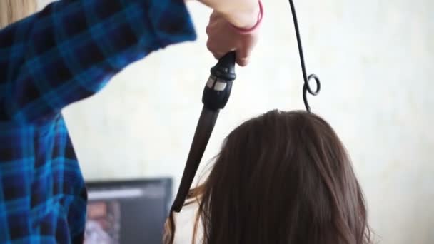 Menina com um ferro de ondulação fazendo seu cabelo — Vídeo de Stock