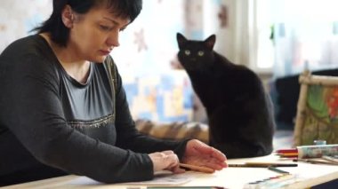 Kadın bir kalem ile kuş çizer.