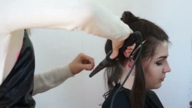 Kuaför saçı saç maşasıyla çevirir.